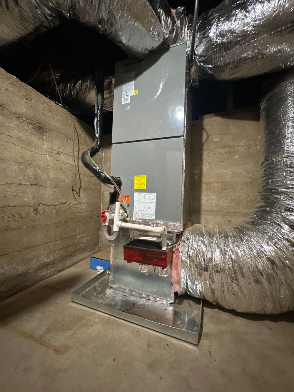 Modern furnace installation in a basement with insulated ductwork and ventilation.